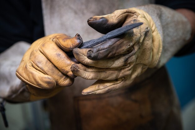 Photo deux mains d'homme fabriquent un couteau en acier