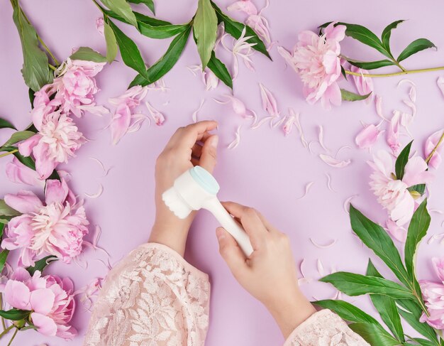 Deux mains d&#39;une jeune fille à la peau lisse et un bouquet de pivoines roses