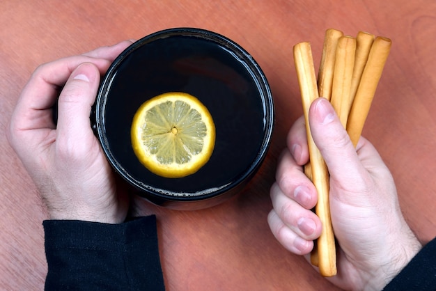 Deux mains avec une tasse de thé et des biscuits se bouchent