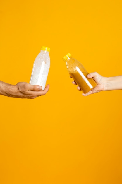 Deux mains tenant des bouteilles avec des boissons