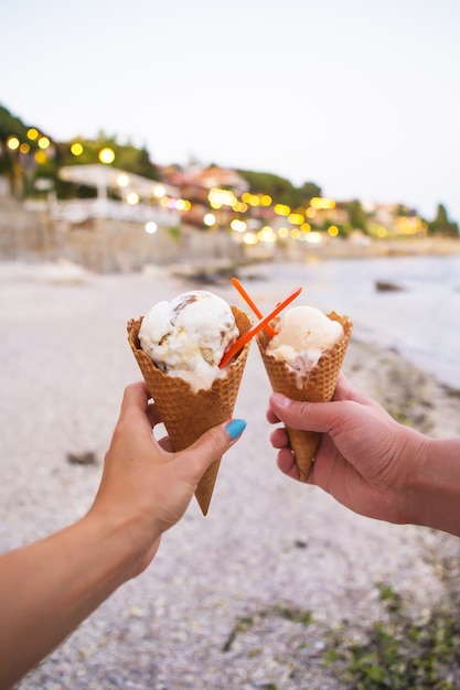 Deux mains tenant une délicieuse glace sur une plage d'été, gros plan.