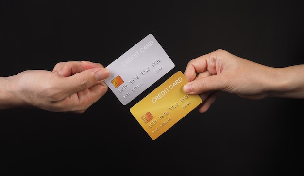 Deux mains tiennent une carte de crédit en argent et en or sur fond noir x9
