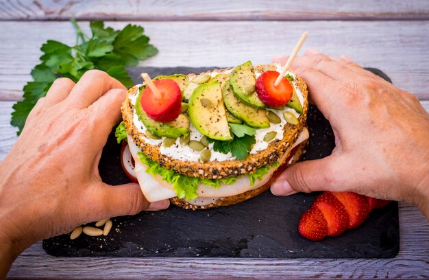 Deux mains tiennent un sandwich complet à trois couches avec de la dinde rôtie avec de la laitue et de la tomate