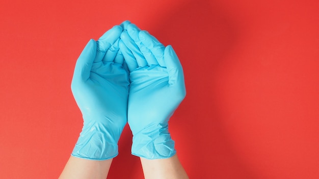 Deux mains vides avec des gants sur fond rouge.