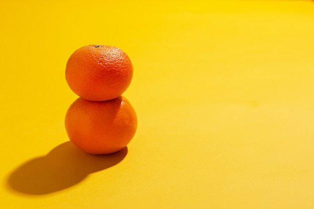 Deux mandarines avec des feuilles en pile sur fond jaune