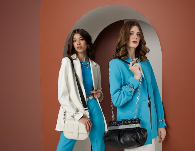 Deux mannequins dans des looks blancs bleus aqua Veste blazer jupe haut pantalon pantalon sacs à main