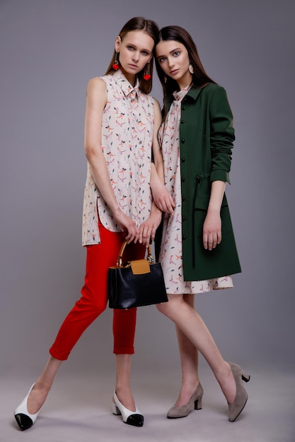 Deux mannequins en haut à motifs clairs, pantalon rouge sans manches et manteau vert avec sac