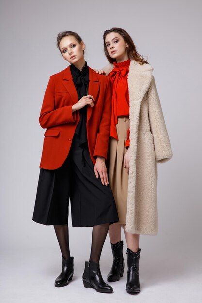 Deux mannequins en pantalon court noir manteau beige jupe longue chemisier arc