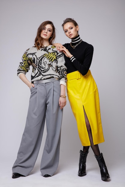 Deux mannequins en pantalon gris pantalon chemisier noir jupe longue en cuir jaune