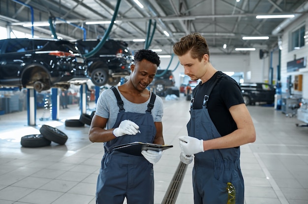 Deux mécaniciens masculins parlant au service de voiture