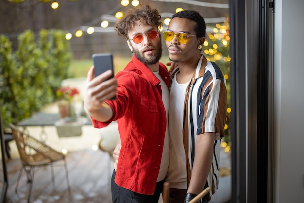 Deux mecs élégants vêtus de couleurs vives prenant un selfie au téléphone à l'intérieur