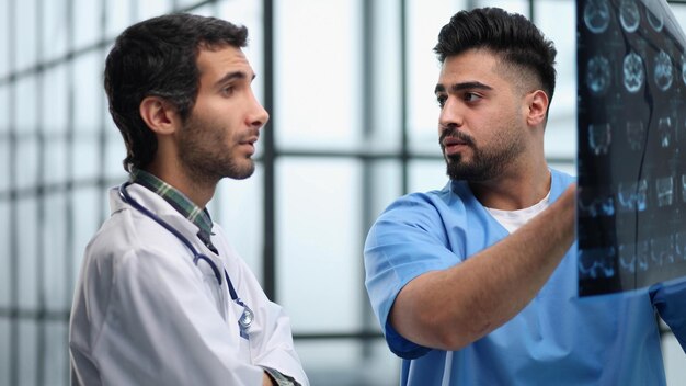 Deux médecins masculins regardant une radiographie cérébrale