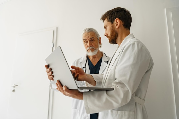 Photo deux médecins regardent quelque chose sur l'ordinateur portable dans le bureau du médecin