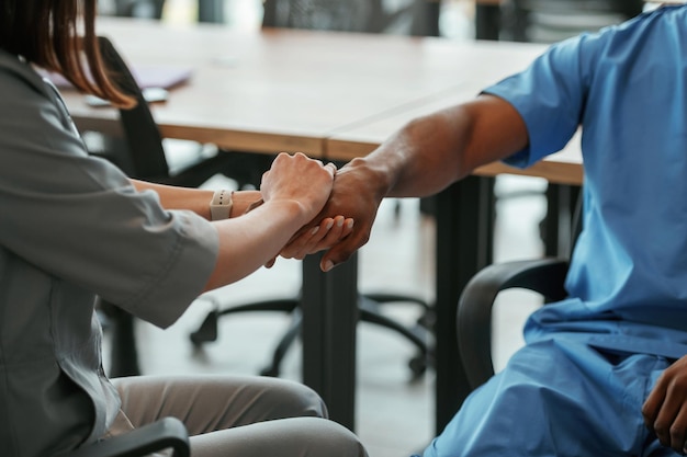 Photo deux médecins se tiennent la main à l'intérieur.