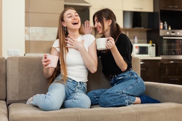 Deux meilleures amies émotionnelles parlant de tout en étant assises sur le canapé et en buvant du thé dans le salon