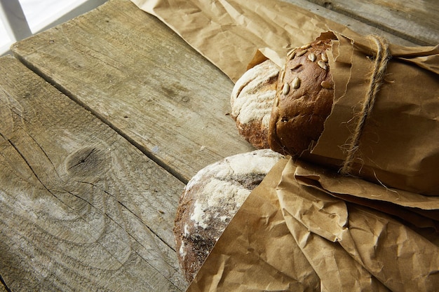 Deux miches de pain emballées dans du papier sur une table en bois