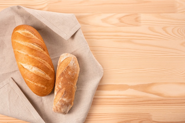 Deux miches de pain sur une serviette en textile sur une table en bois. Délicieux pain frais. concept de recette de coût ou de pain.