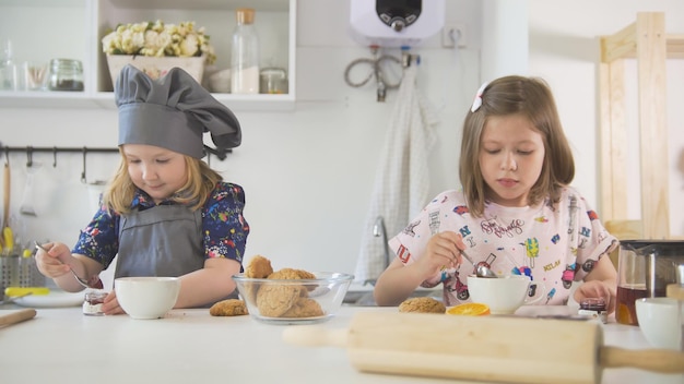 Deux mignonnes petites filles décorant des biscuits avec de la confiture se bouchent