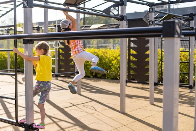 Deux mignonnes petites filles s'amusant sur une aire de jeux à l'extérieur en été. Activités sportives pour les enfants.