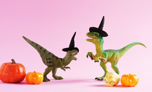 Photo deux mignons dinosaures verts heureux avec des citrouilles sur un fond rose