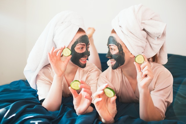 Deux modèles féminins font un masque facial et utilisent du concombre vert frais