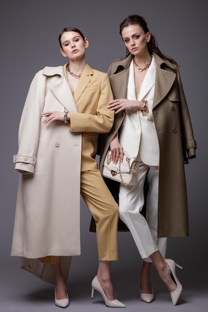 Deux modèles de haute couture en manteau blanc beige costume veste pantalon pantalon accessoires sacs à main