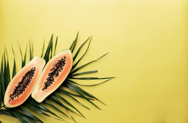 Photo deux moitiés de fruits tropicaux de papaye fraîche comme concept d'alimentation saine sur la feuille de palmier vert