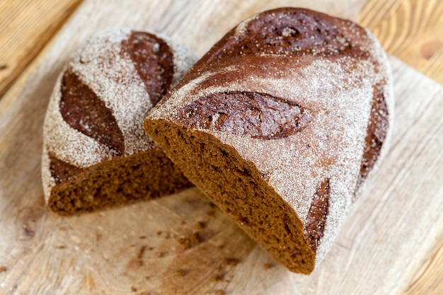 Deux moitiés de pain noir aromatique cuit à partir de farine de seigle. Le pain est coupé en deux pendant la cuisson. fermer