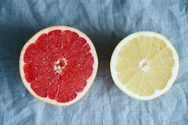 Deux moitiés de pamplemousse rouge et blanc, cercles lumineux sur un lin gris foncé