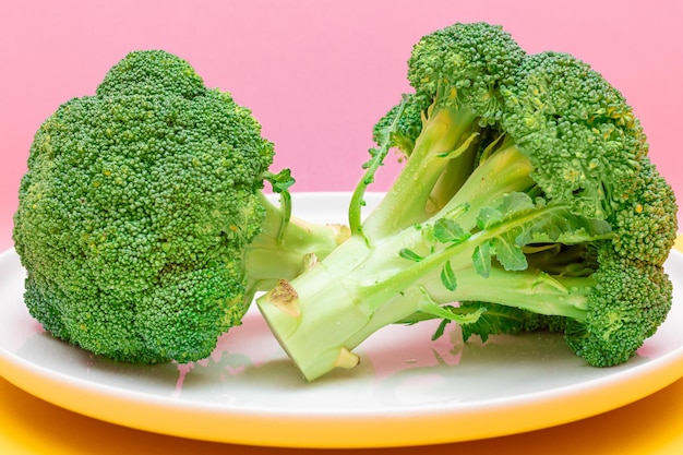 Deux morceaux de brocoli frais et crus sur une plaque blanche de chou vert non cuit