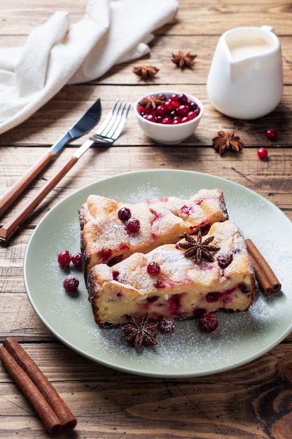 Deux morceaux de casserole de tarte au fromage cottage avec des canneberges et des épices cannelle et anis sur une assiette.