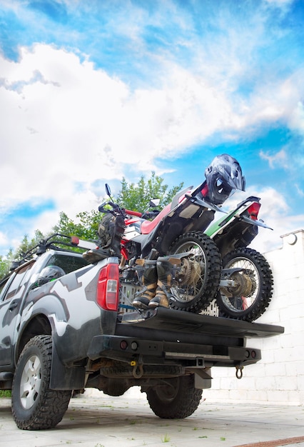 Deux motos tout-terrain à l'arrière du camion camo avec des équipements de sécurité, tels que des bottes de moto et des casques.