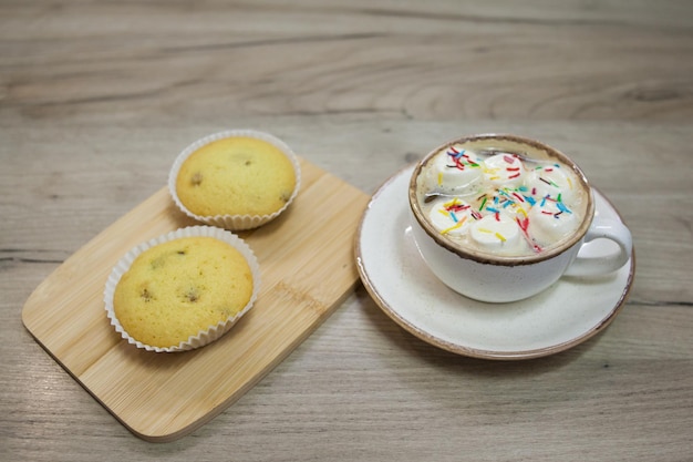 Deux muffins aux raisins secs sur un plateau en bois et une tasse de chocolat chaud