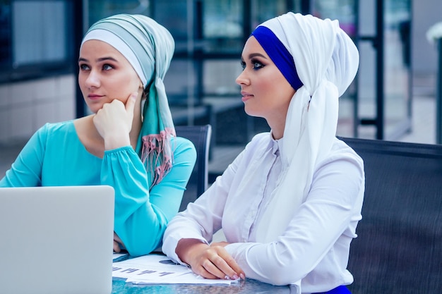 Deux musulmans de race blanche, dame de bureau discutant avec une femme d'affaires partenaire d'un entretien d'embauche au bureau châle et turban sur la tête peau et maquillage parfaits