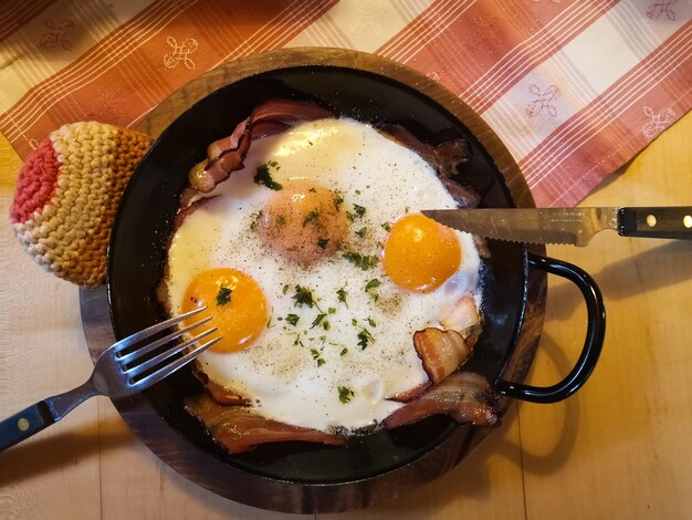 Deux œufs au plat et bacon dans une casserole pour le petit-déjeuner en vacances en autriche