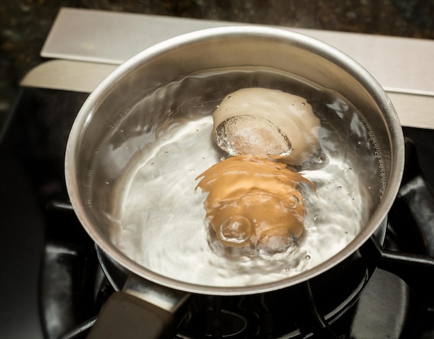 Deux oeufs bouillants dans une casserole en acier inoxydable