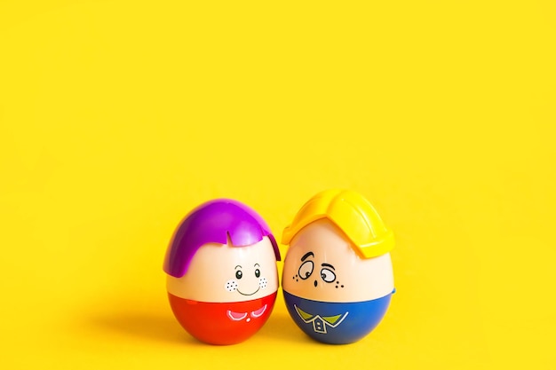 Deux œufs drôles, un garçon et une fille avec des visages sur un fond jaune.