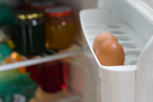 Deux œufs de poule sur une étagère de la porte de réfrigérateur