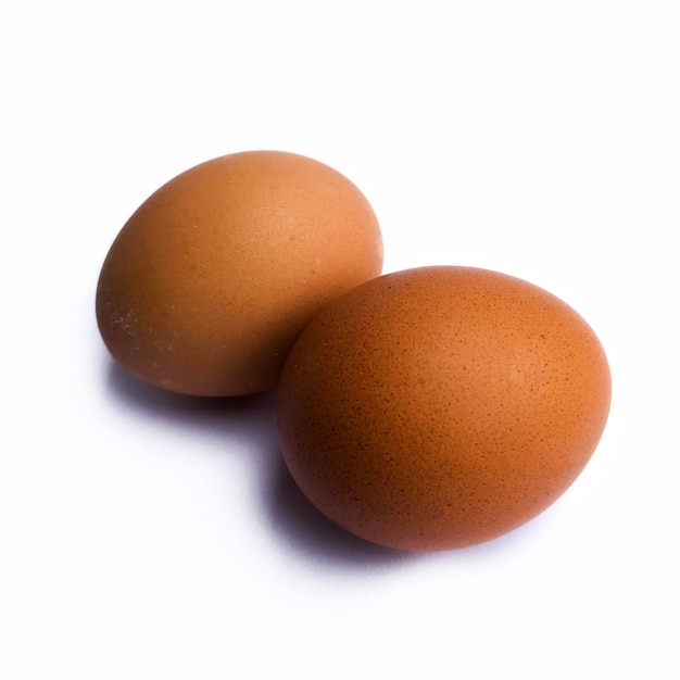 Photo deux œufs de poule isolés sur un fond blanc