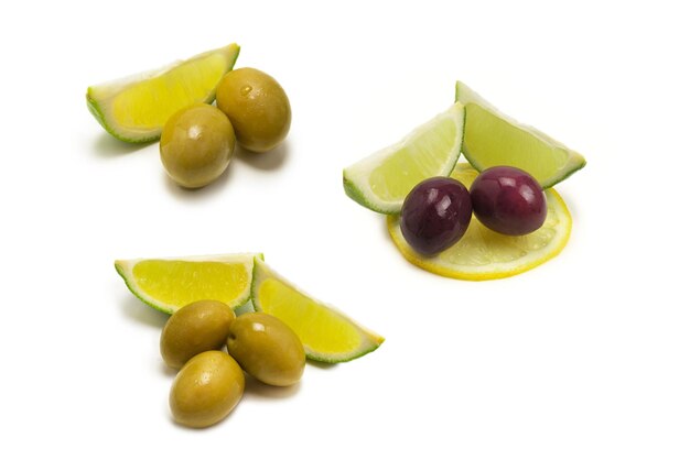 Deux olives et un morceau de citron et de citron vert isolés sur fond blanc