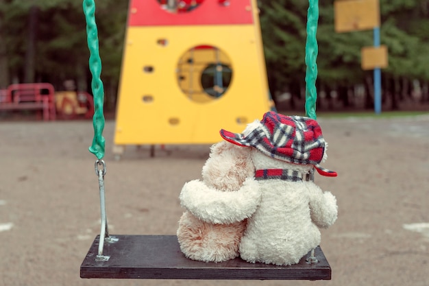 Deux ours en peluche s'embrassant assis sur une balançoire. Le concept d'amour, de relations.