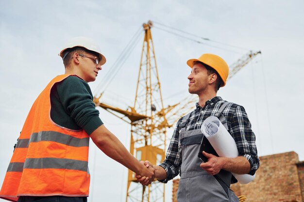 Photo deux ouvriers de la construction en uniforme et équipement de sécurité ont le travail de construire ensemble