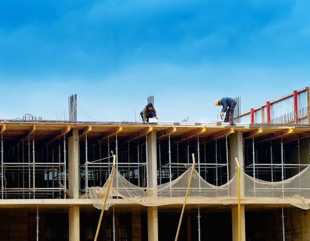 Deux ouvriers sur le fond du chantier de construction du toit