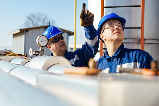 Deux ouvriers d'usine dans un casque sur l'équipement lourd et le pipeline