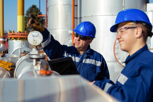 Photo deux ouvriers d'usine dans un casque sur l'équipement lourd et le pipeline