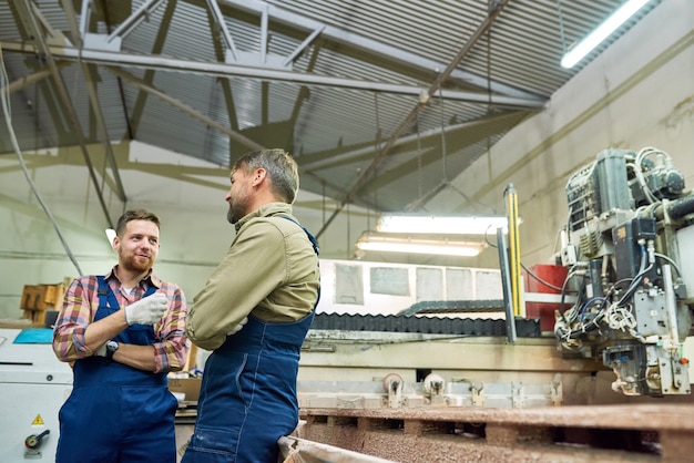 Deux ouvriers d'usine discutant en atelier