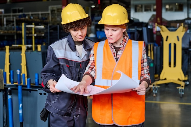 Deux ouvriers d'une usine moderne portant des casques de protection et des vêtements de travail