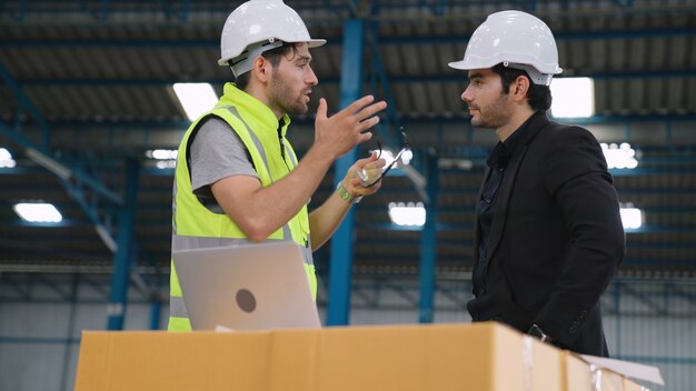 Deux ouvriers d'usine travaillant et discutant du plan de fabrication dans l'usine . Concept d'industrie et d'ingénierie.