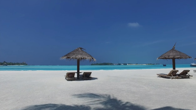 Deux parasols avec chaises longues sur la plage des Maldives