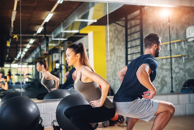 Deux partenaires de gym concentrés et forts faisant des squats appuyés l'un sur l'autre.